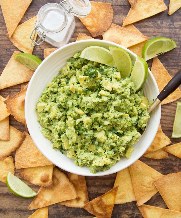 overhead shot of bowl of guac with tortilla chips surrounding