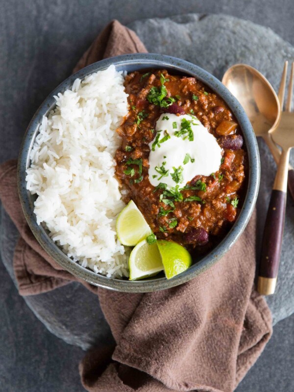 overhead shot of chilli in a bowl served with golden spoon and fork on slate