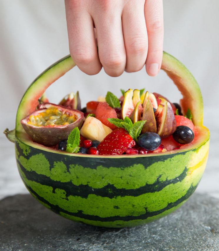 hand holding the handle of a watermelon fruit basket