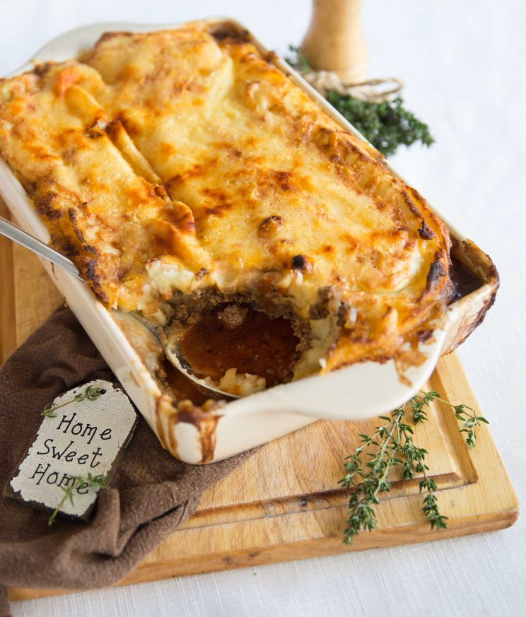 cottage pit served on wooden board with serving spoon dug in showing gravy