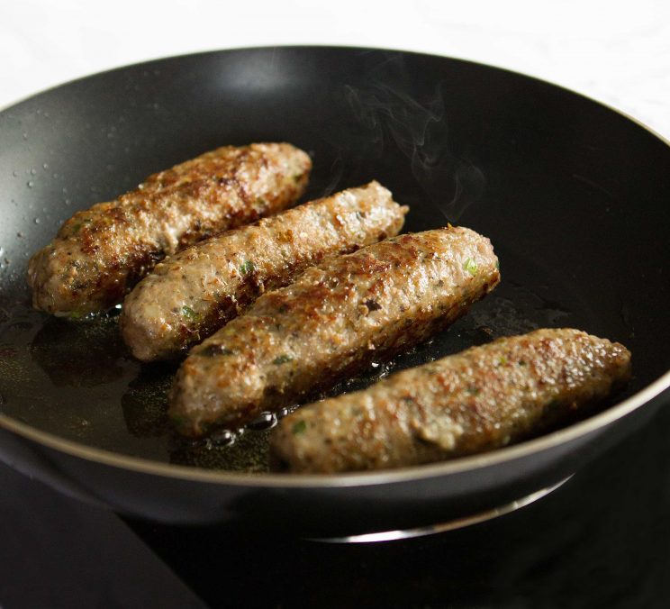 sausages in frying pan with steam coming off