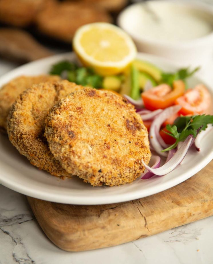 tuna patties plated with salad on white plate with dip and more patties blurred in background