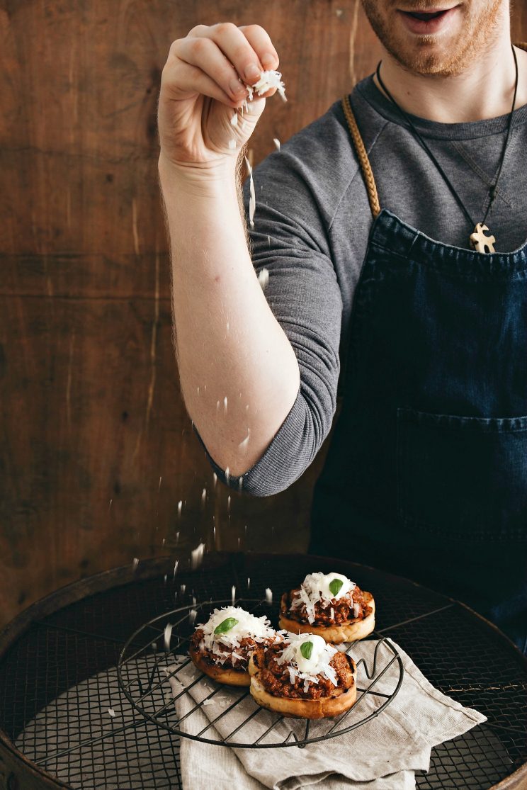 chris collins sprinkling parmesan over bolognese sliders