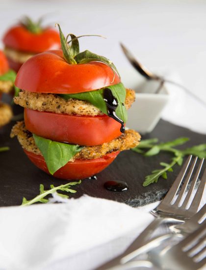 Stacked Tomato and Fried Mozzarella Salad with Balsamic Glaze dripping down the basil leaf