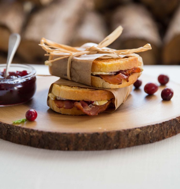 brie toasties stacked on wooden board wrapped in paper parcels with string bow