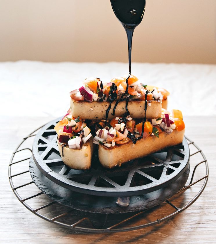 drizzling balsamic glaze over feta bruschetta