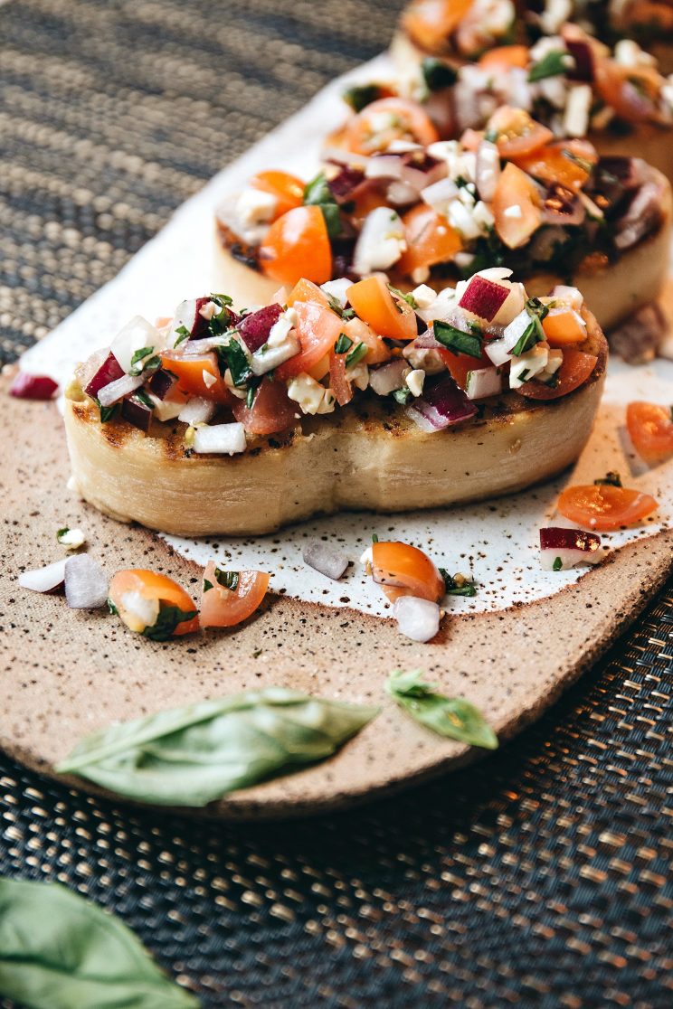 close up shot of bruschetta on plate garnished with basil
