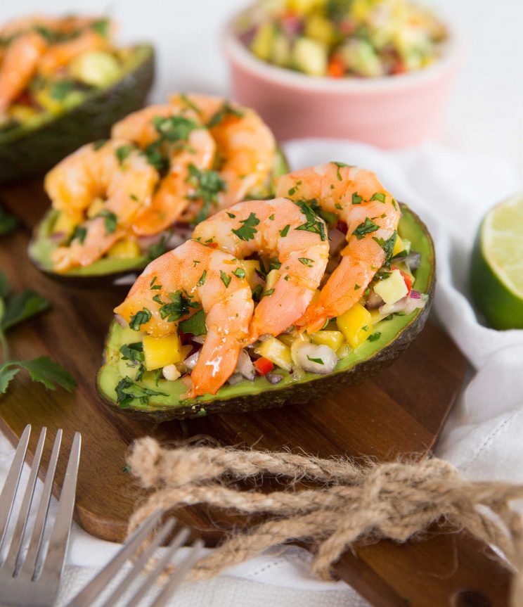 side shot of stuffed avocados lined up on chopping board