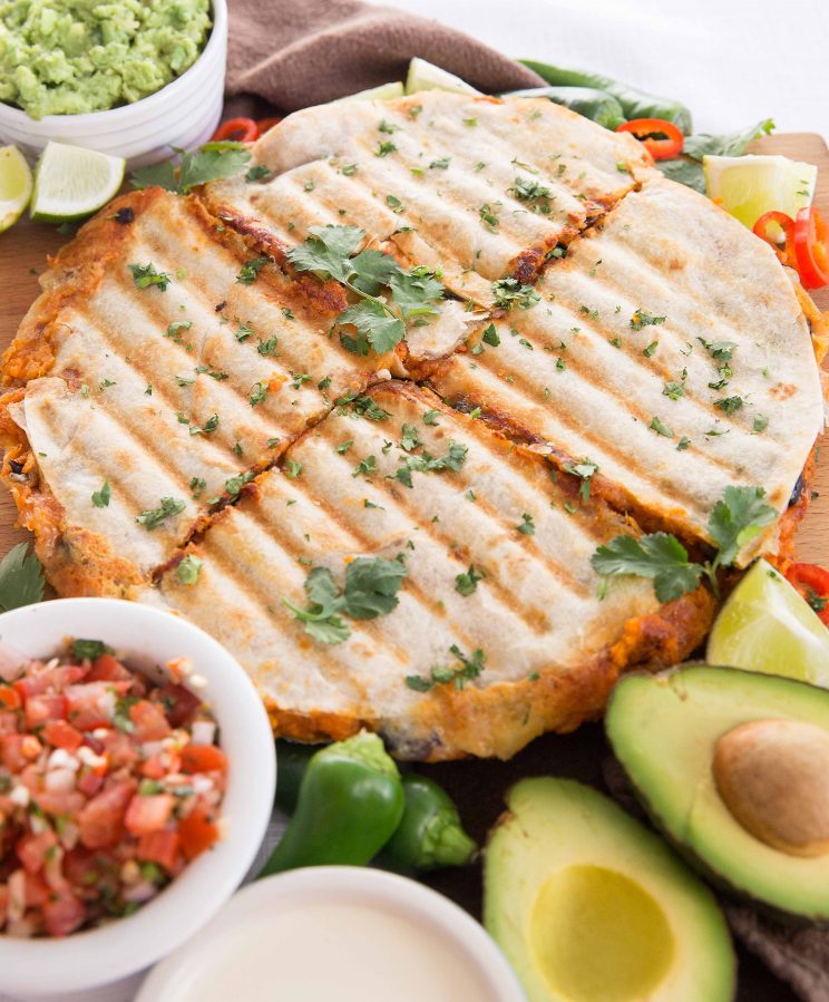 closeup shot of whole quesadilla on board garnished with coriander