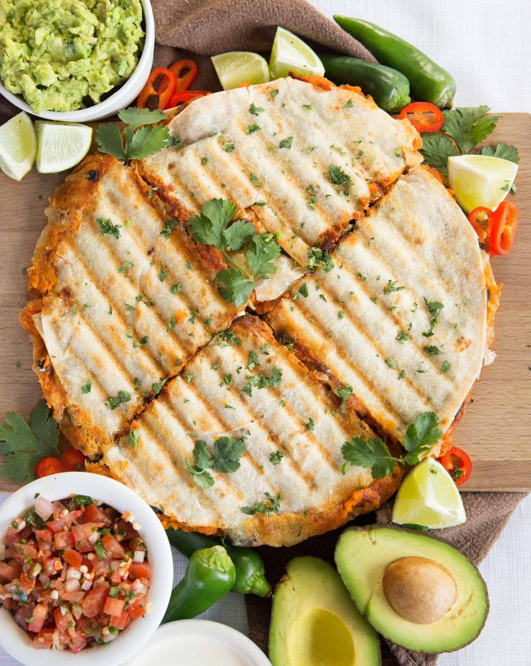 overhead shot of quesadillas sliced into 4 garnished with chilli, jalapeno and coriander