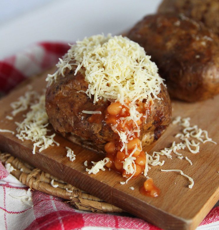 jacket potato with beans and cheese with beans pouring out on chopping board