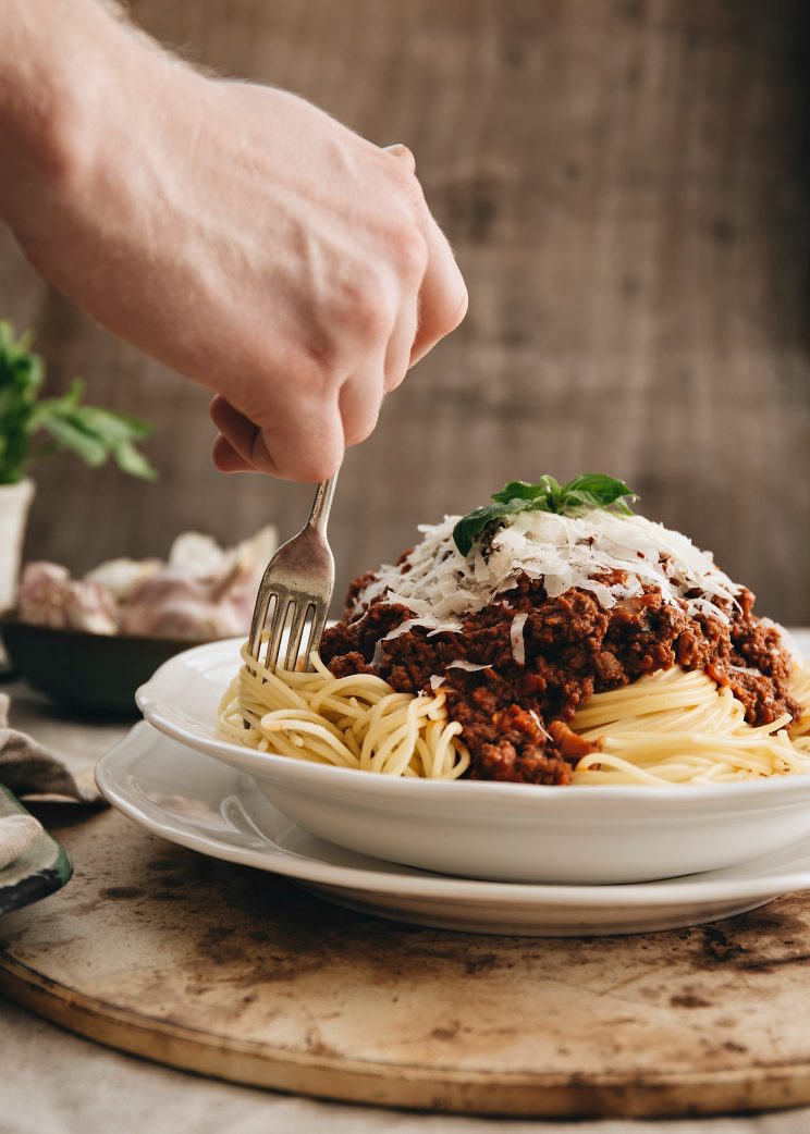 hand twisting fork into spaghetti bolognese