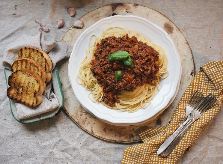 The Best Spaghetti Bolognese Recipe spaghetti bolognese overhead shot with garlic bread and forks