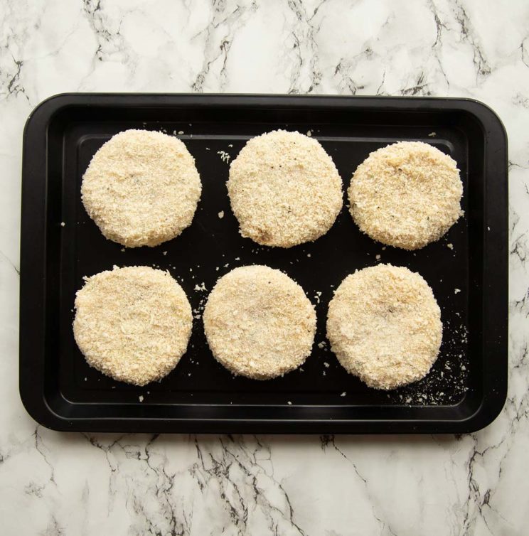 overhead shot of tuna patties on black baking tray ready to go in oven