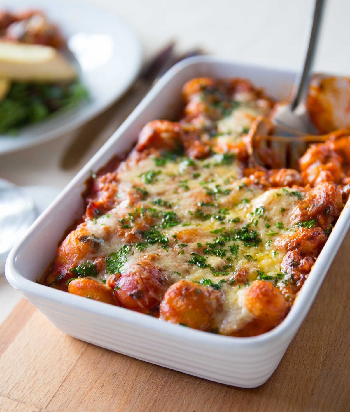 gnocchi in baking dish with silver spoon digging in