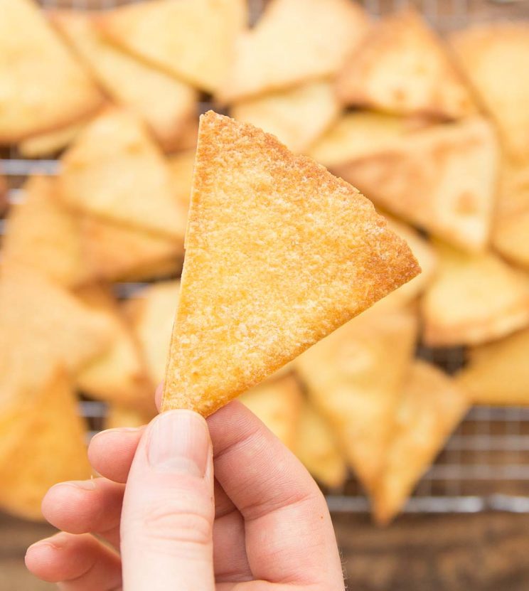 closeup overhead shot of hand holding tortilla chips with plenty more blurred in the background