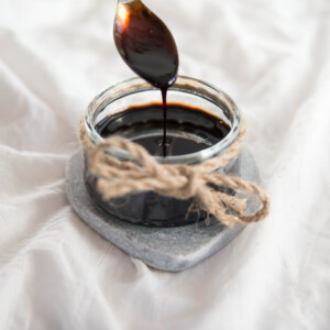 drizzling balsamic glaze into glass jar with tsp