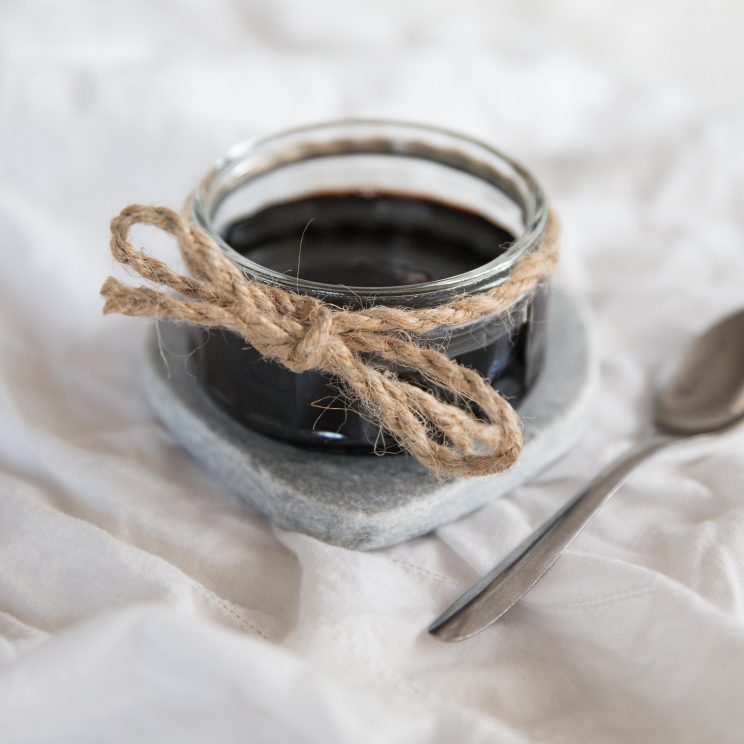 Homemade Balsamic Glaze in glass jar on white sheet with tsp