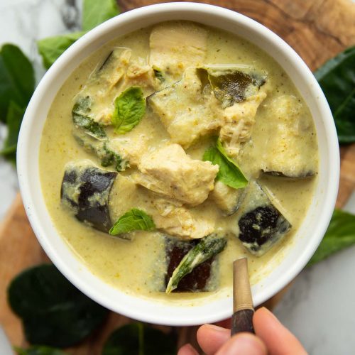 overhead shot of curry in white bowl with gold spoon digging in