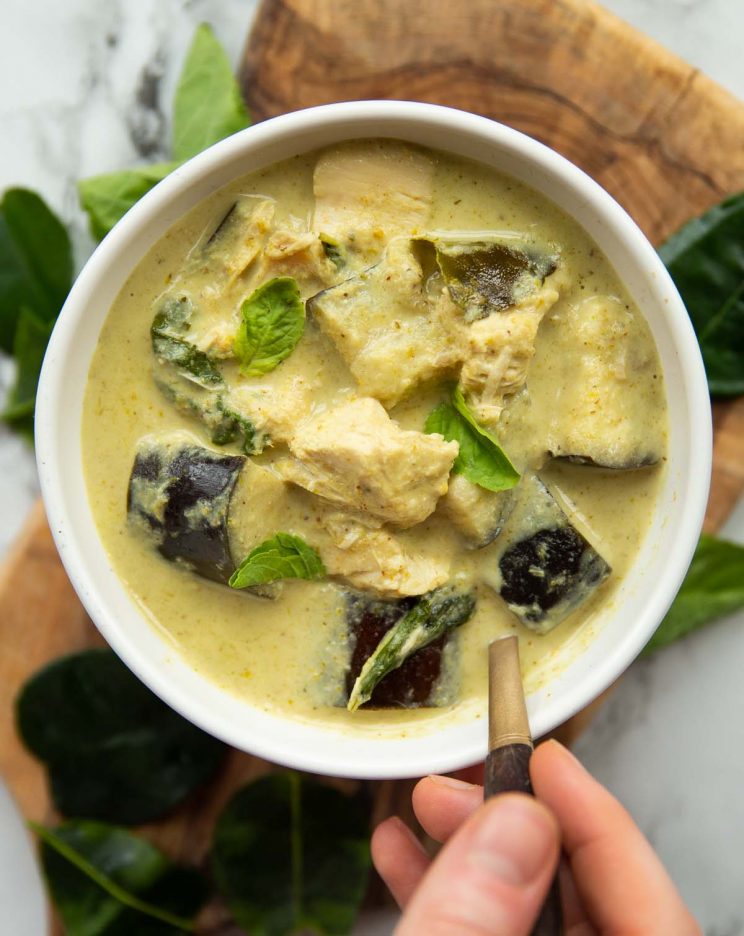 overhead shot of curry in white bowl with gold spoon digging in