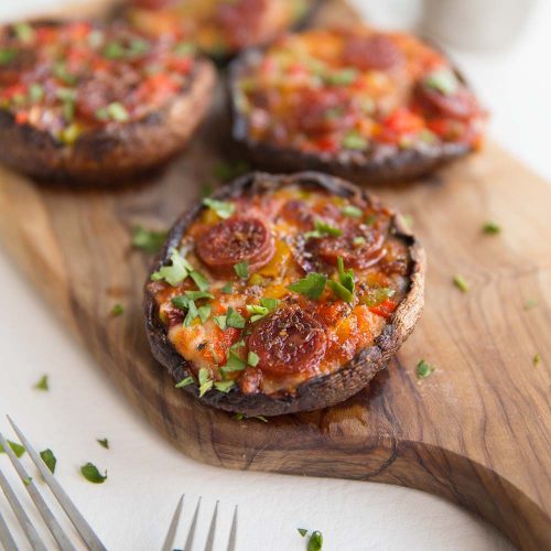 pizza mushrooms served on wooden chopping board garnished with parsley