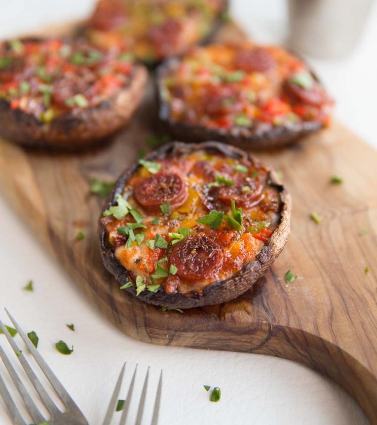 pizza mushrooms served on wooden chopping board garnished with parsley