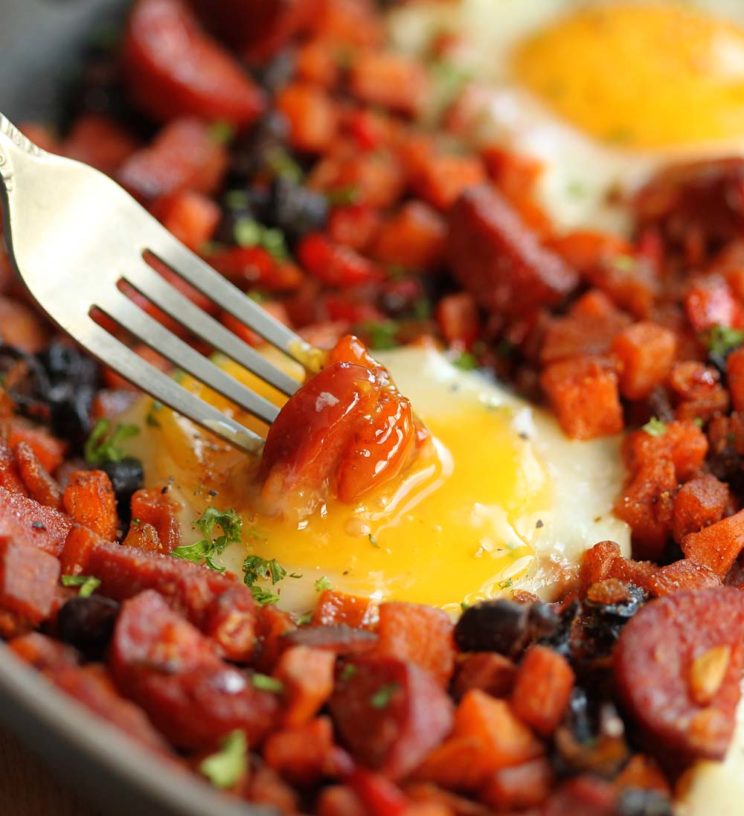 dipping chorizo into egg yolk in skillet