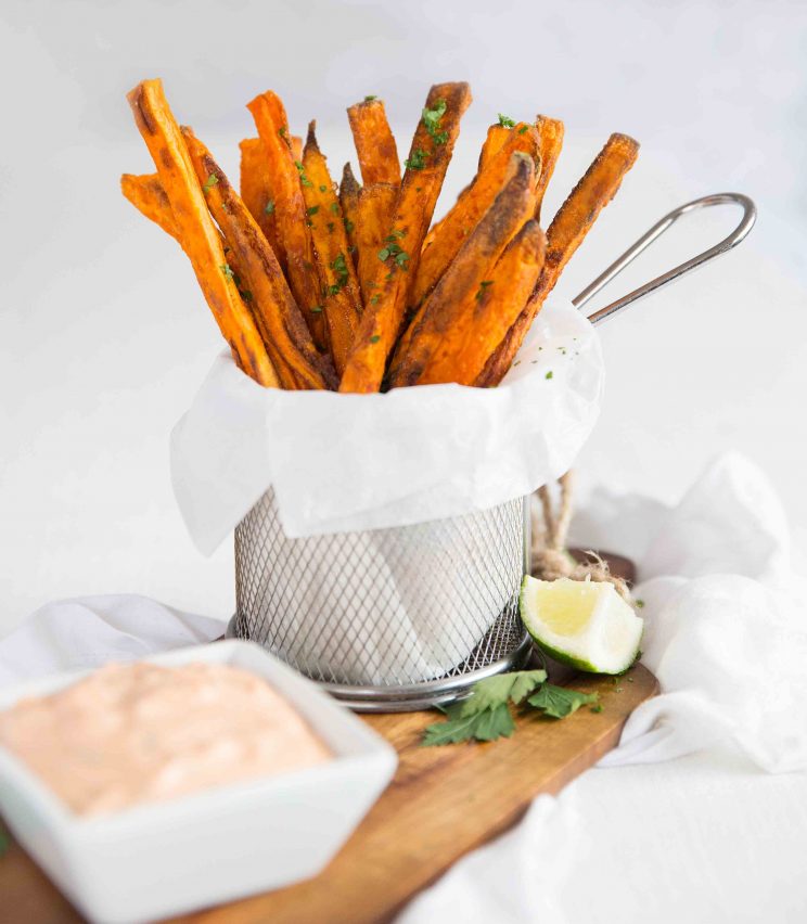 sweet potato fries in a small pot on chopping board with small white pot of dip