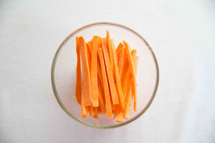 overhead shot of sweet potato fries soaking in glass bowl of water
