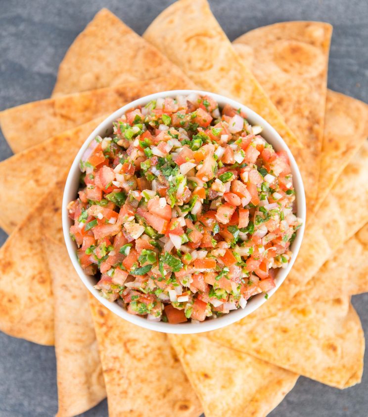 overhead shot of salsa in a white bowl surrounded by tortilla chips