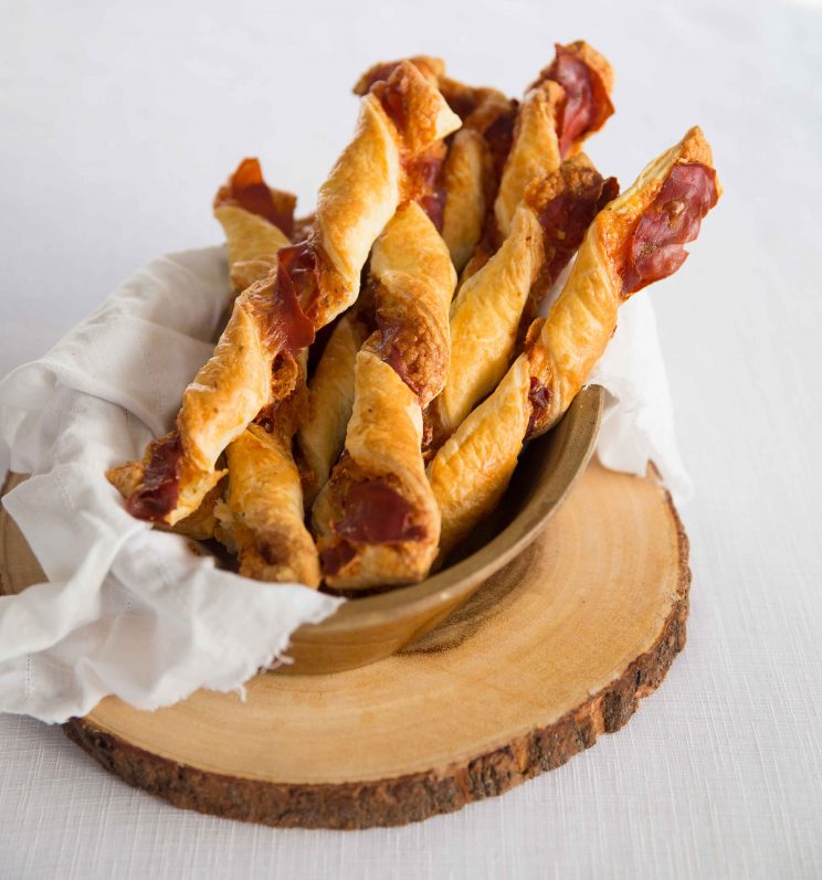cheese prosciutto twists in basket on wooden block