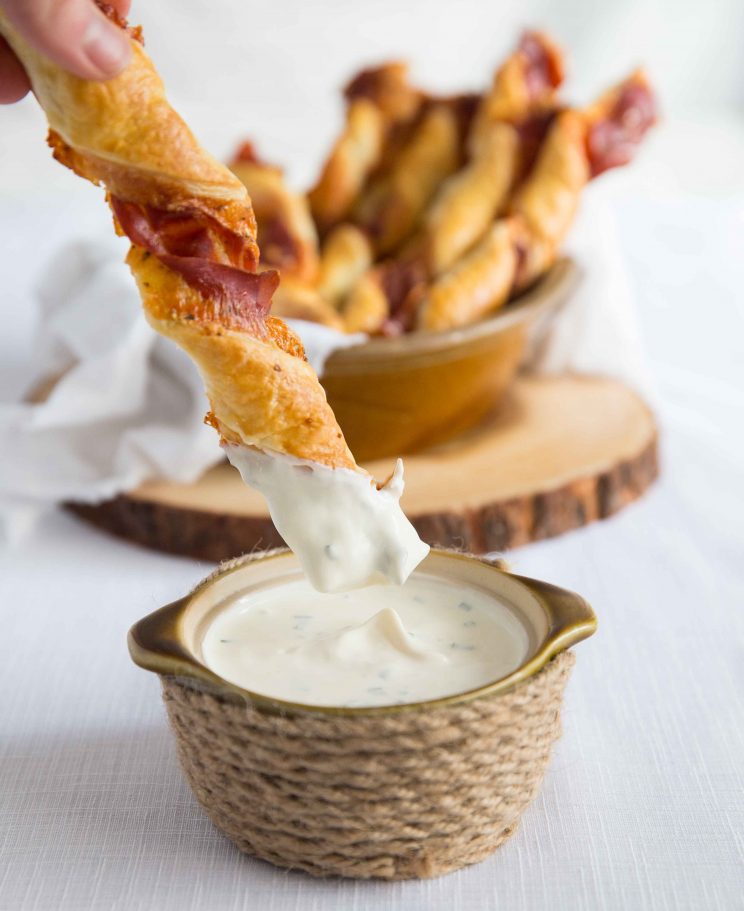 dunking a cheese and prosciutto twist into small pot of dip