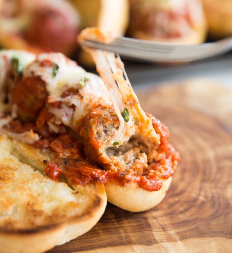 meatball sub with cheese being pulled out the centre of one of the meatballs