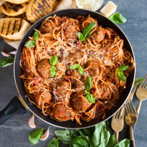 overhead shot of spaghetti meatballs in skillet with fresh basil and parmesan