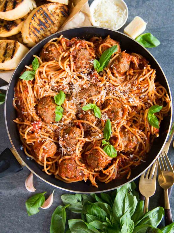 overhead shot of spaghetti meatballs in skillet with fresh basil and parmesan
