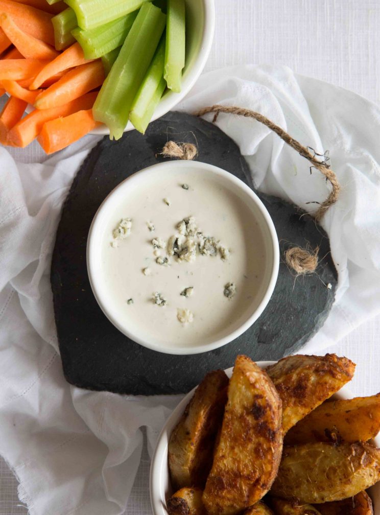 blue cheese dip in white pot with carrots, celery and potato wedges