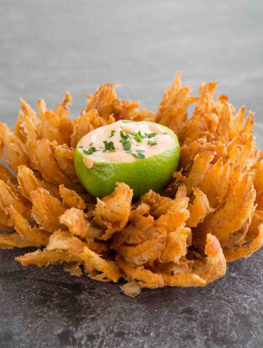 blooming onion served with lime dipping bowl in the centre on slate