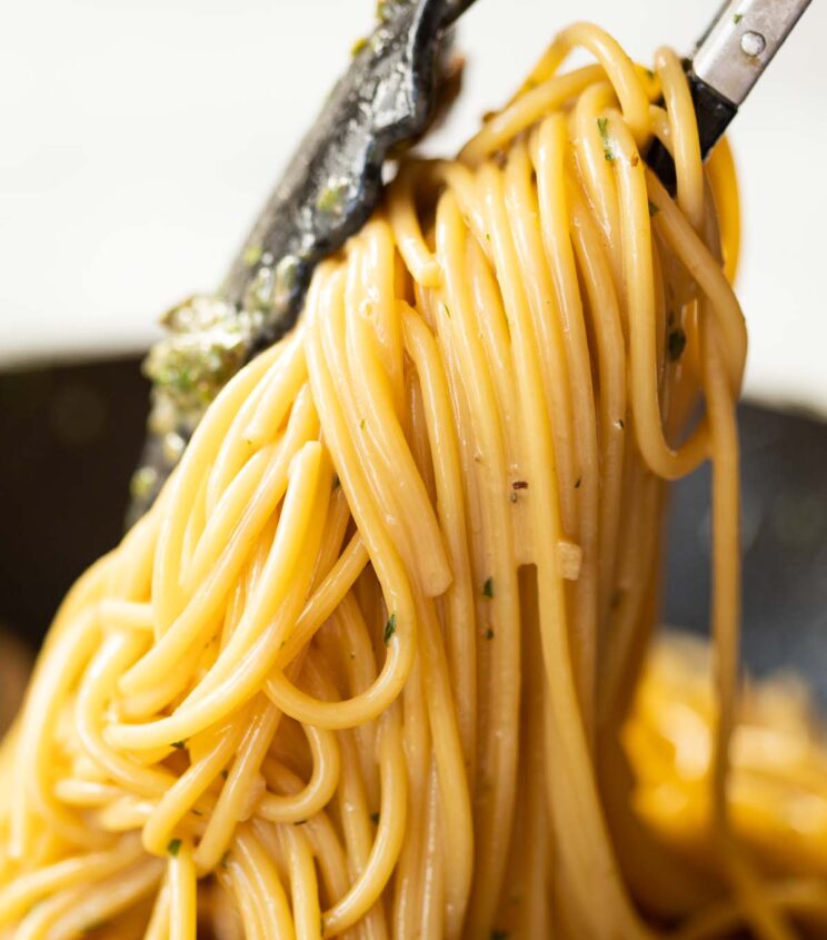 close up shot of pasta tongs lifting up spaghetti from pan