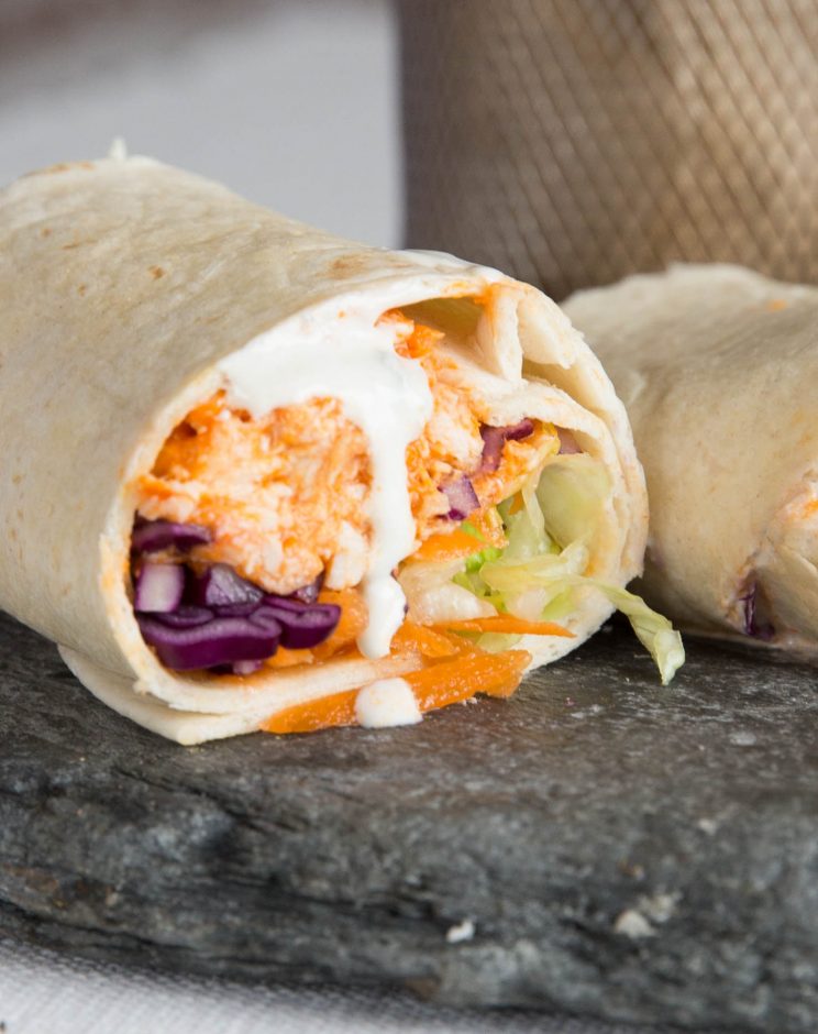 closeup shot of buffalo chicken wraps with blue cheese sauce dripping down