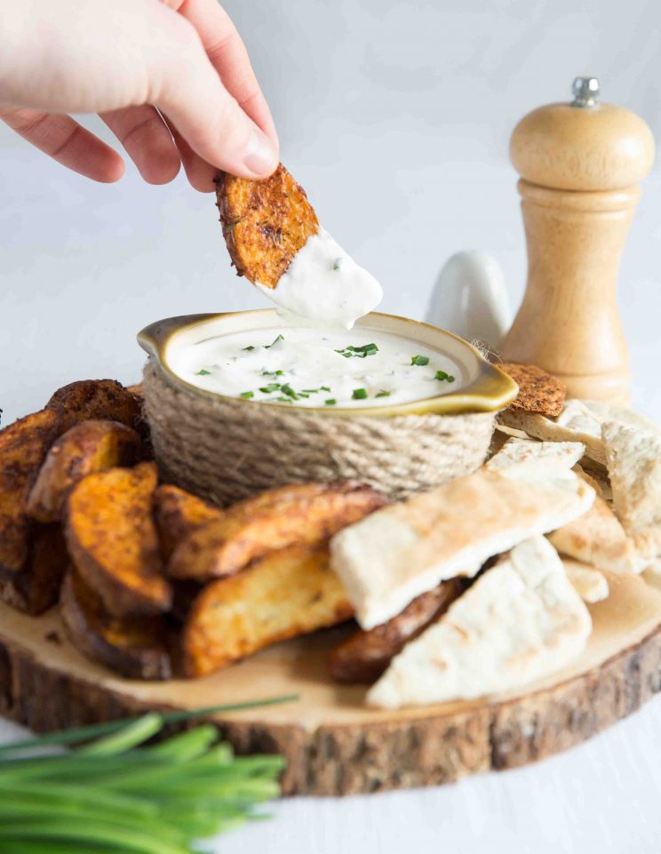 dunking a potato wedge into dip