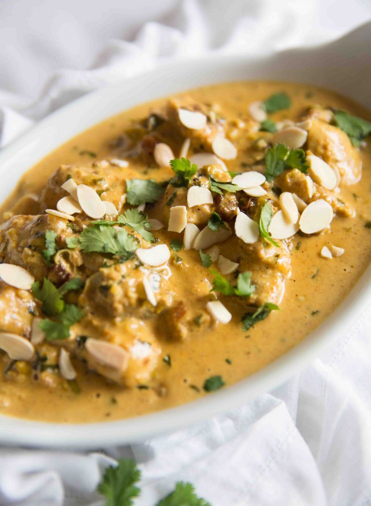 closeup shot of coronation chicken in oval shaped bowl garnished with flakes almonds