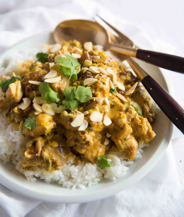 Coronation Chicken served with rice in a white bwol with golden spoon and fork