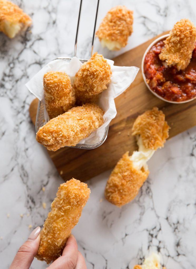 overhead shot of halloumi fries scattered on surface with hand taking one