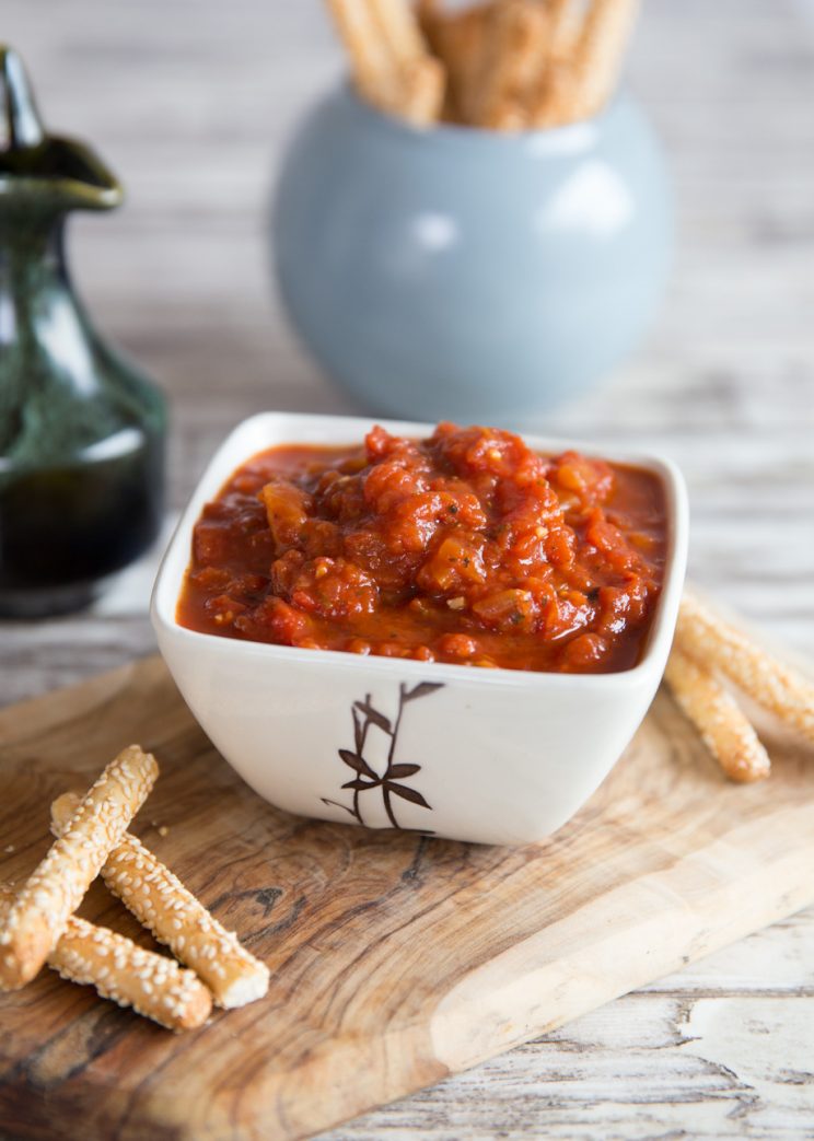 pot of sauce on wooden board with breadsticks blurred in the background