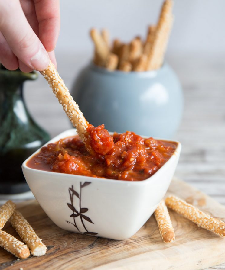 dunking a breadstick in dip with more breadsticks blurred in the background