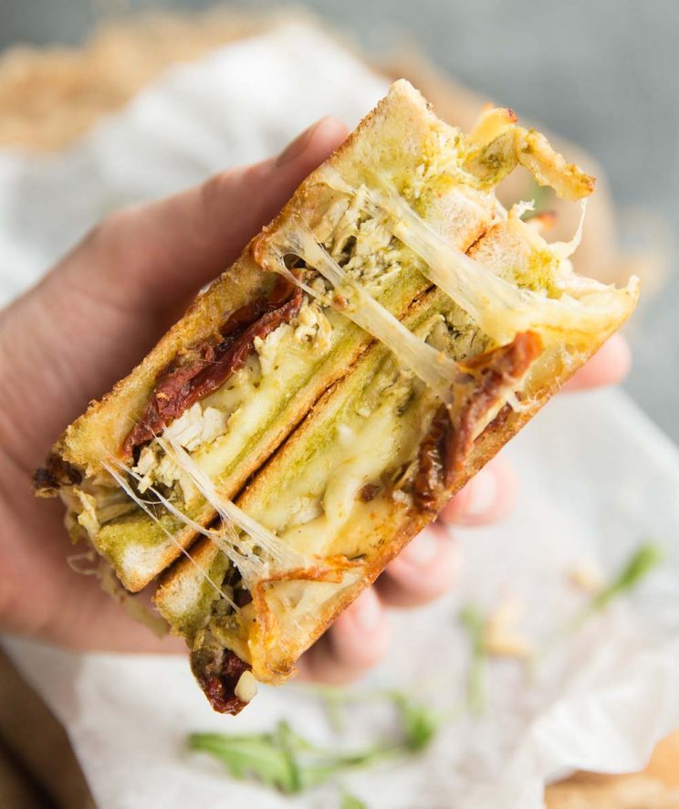 Grilled cheese open with cheese pull and sun dried tomatoes showing