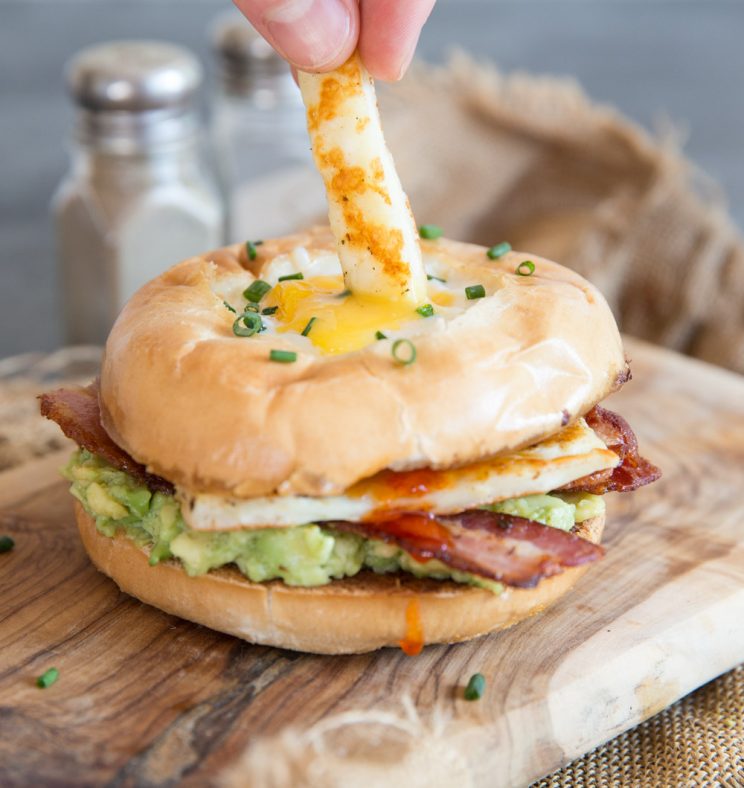 dipping halloumi stick into egg in a hole bagel