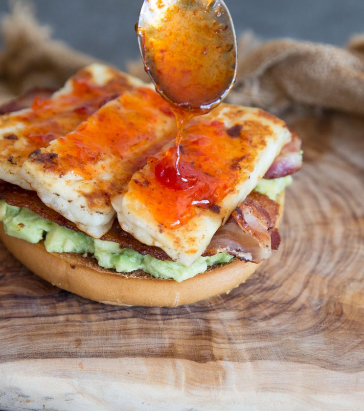 close up shot of Egg in a Hole Breakfast Bagel with Chilli Jam dripping off spoon