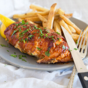 Triple Cheese Stuffed Chicken Wrapped in Bacon with chips and lemon wedges