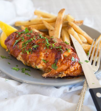Triple Cheese Stuffed Chicken Wrapped in Bacon with chips and lemon wedges